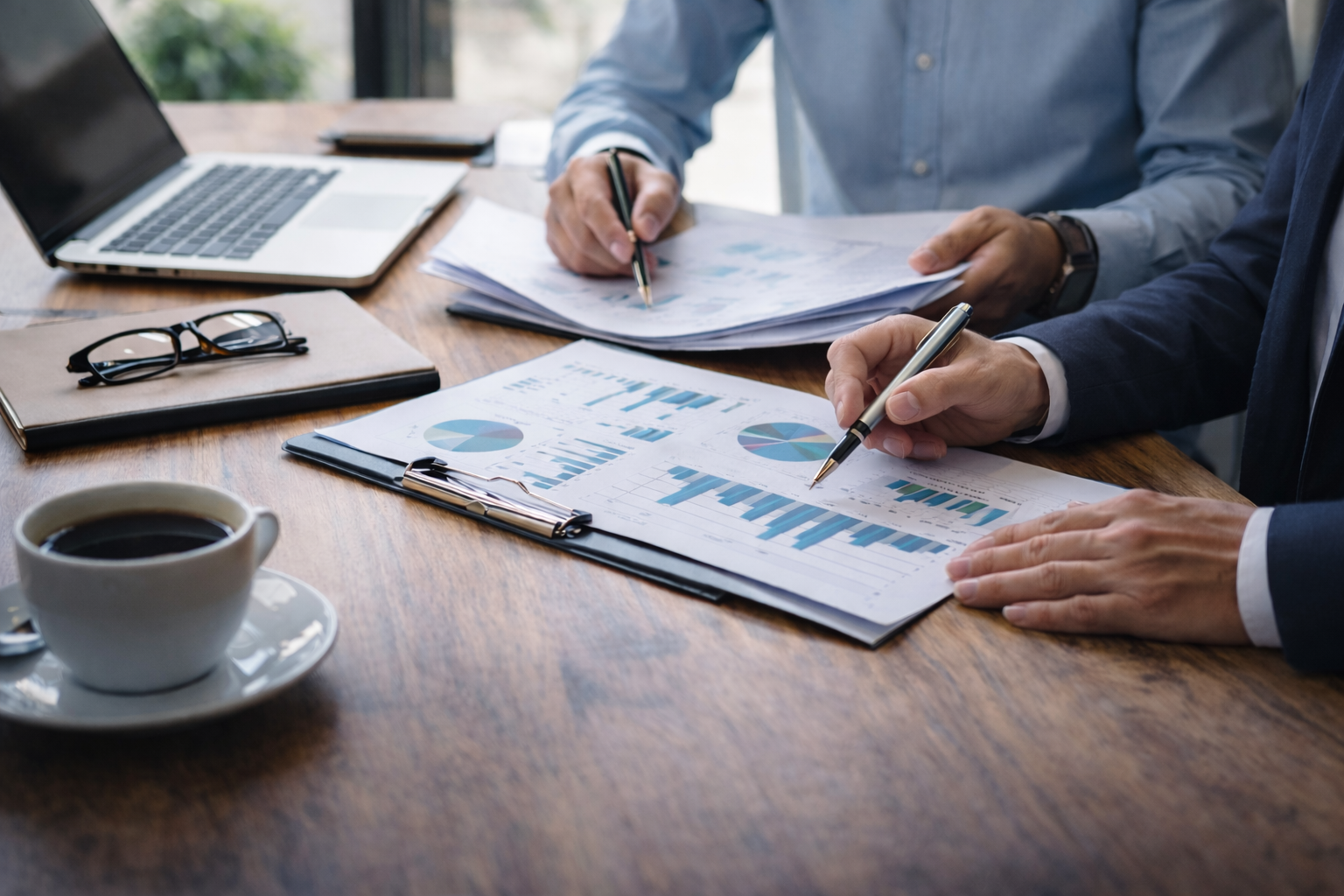 Two business professionals reviewing financial statements and valuation reports while evaluating a Mississippi business for potential acquisition.